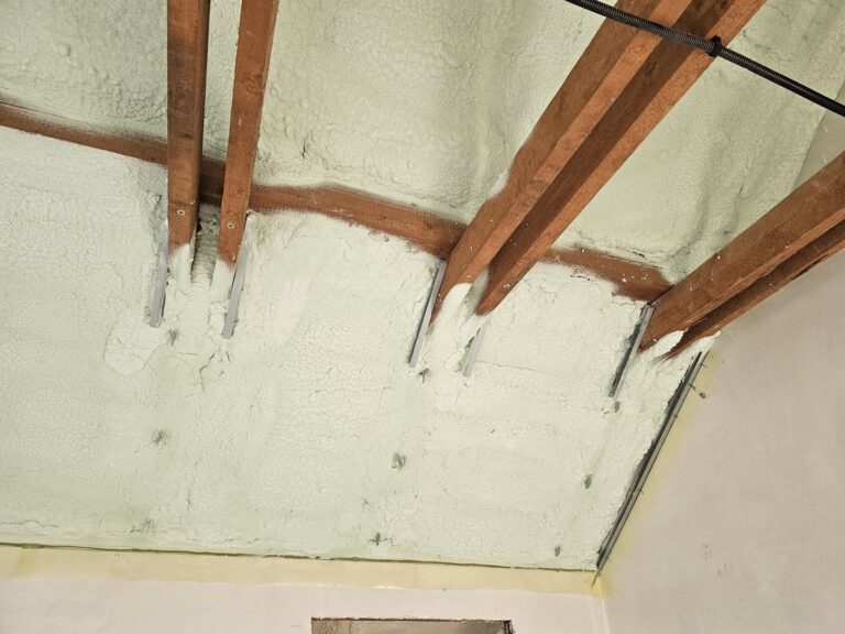 Ocieplony skos poddasza z drewnianymi belkami i metalowymi wieszakami
